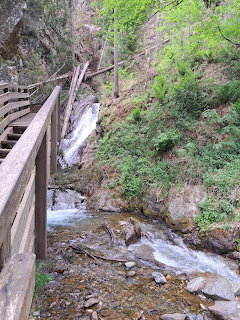 Wooden walkway beside a small waterfall and rocky forest stream in Krakaudorf, Austria.