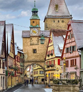 Medieval tower gate with clock in German town street lined with colorful half-timbered buildings