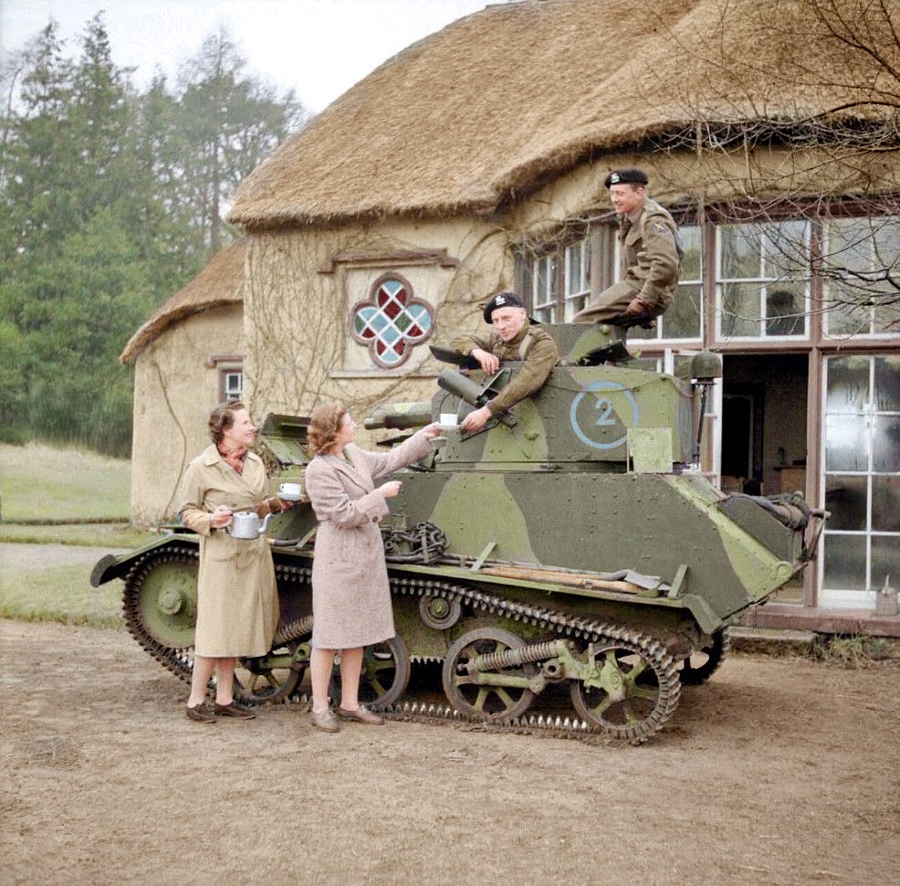 Vintage British Light Tank MkVI outside a thatched cottage with soldiers and three women