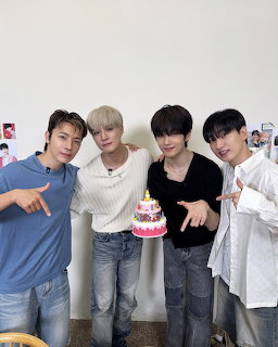 Four young Asian men posing together with a small birthday cake with colorful candles