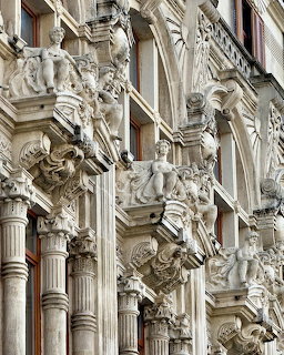 Close-up of ornate Baroque building facade with stone columns, statues, and intricate carved reliefs