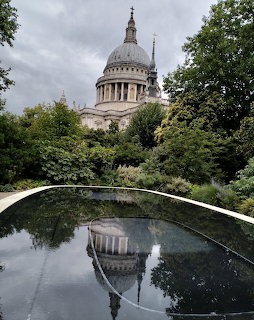 St Paul's Cathedral behind trees with its dome reflected in a calm pond