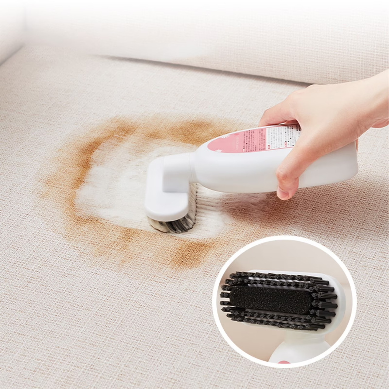 Hand scrubbing a brown stain from a carpet with a white cleaning brush