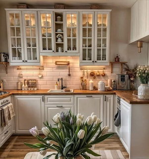 Bright white kitchen with glass cabinets, wood countertops, and tulips in the foreground