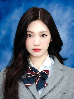 Young Asian woman in grey school blazer with striped bow tie posing for a portrait against blue background