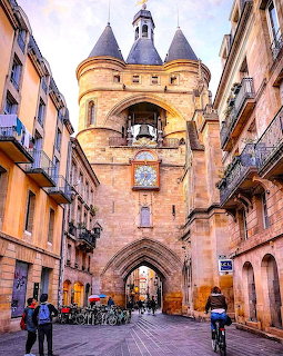 Medieval bell tower gate with twin turrets and clock in Bordeaux city center at twilight
