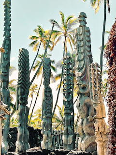 Carved wooden tiki statues and totems among palm trees in Hawaii