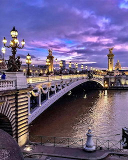 Alexander III Bridge in Paris with ornate lampposts and golden sculptures at twilight over the Seine River