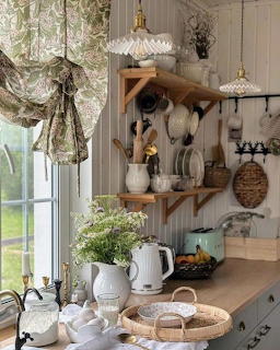Cozy rustic kitchen corner with window, wooden shelves, dishes, flowers, and countertop decor
