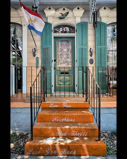 Pastel house entry with turquoise shutters and orange steps bearing a welcoming message
