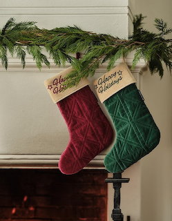Christmas stockings hanging on a fireplace mantel with greenery