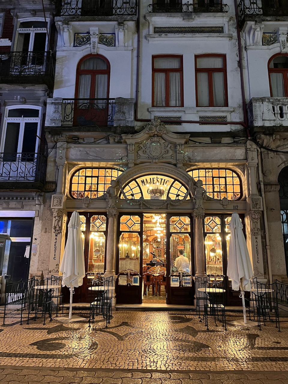 Ornate illuminated Art Nouveau café facade in Lisbon at night with decorative tilework and stained glass