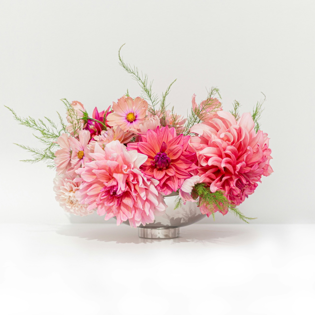 Pink flower arrangement in a clear glass bowl on a white background