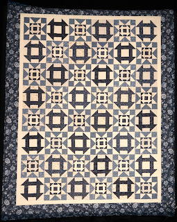 Geometric quilt with navy and cream octagonal blocks and floral border