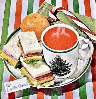 Christmas mug with hot cocoa, cookies, candy cane and orange on striped holiday table setting