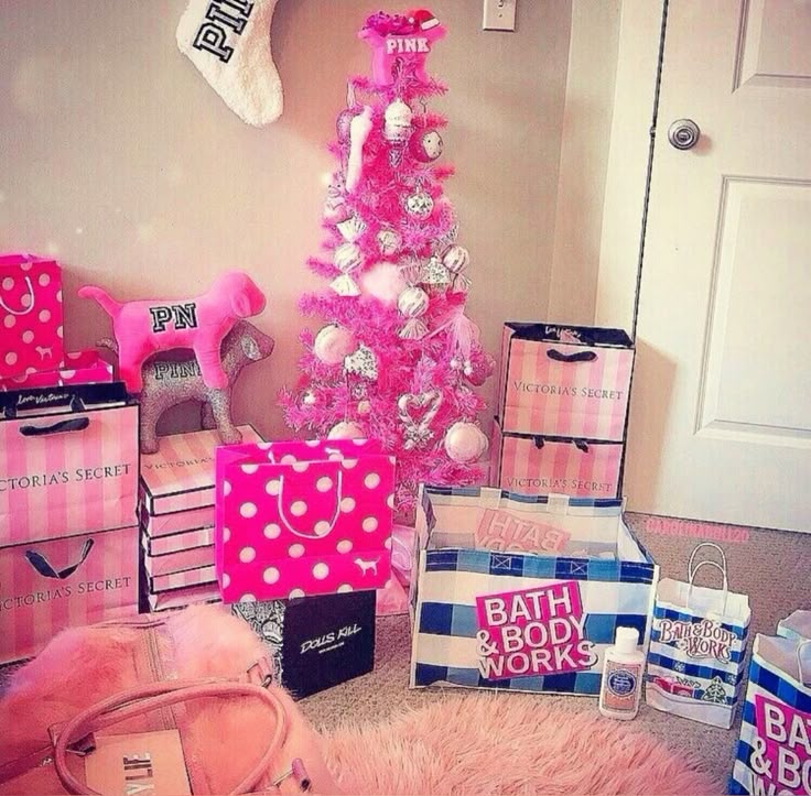 Pink Christmas tree indoors with shopping bags, gift boxes, and pink decorations