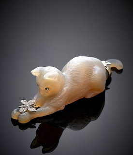 White cat figurine pawing at a butterfly on a black reflective surface