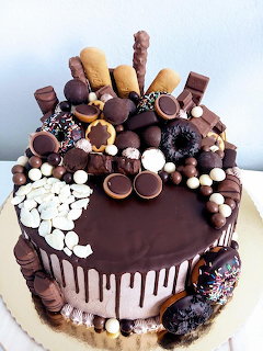 Chocolate drip wedding cake topped with cookies, truffles, donuts, and white chocolate pieces