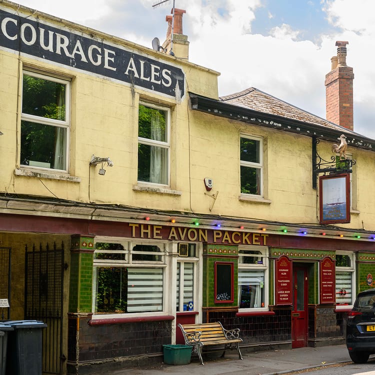 Yellow English pub building with Courage Ales sign and red storefront details