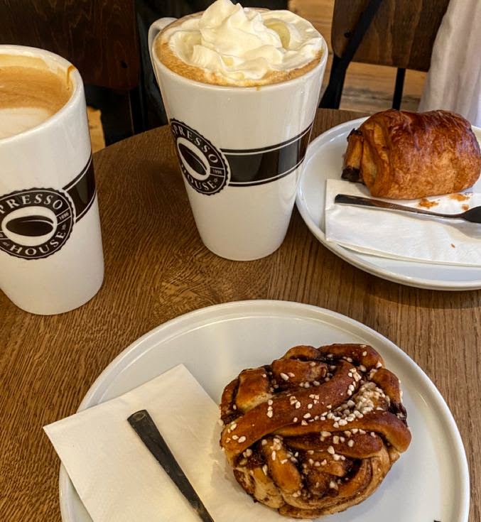Two coffee cups and two pastries on a wooden table at a café