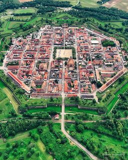 Aerial view of star-shaped fortified town with red roofs surrounded by green fields