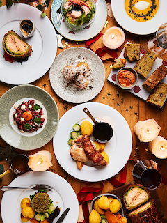 Overhead view of multiple gourmet dishes on white plates arranged on a wooden restaurant table