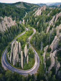 A curving mountain road winding between granite spires and pine forest
