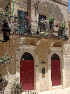 Traditional Maltese limestone townhouse with balconies and red doors