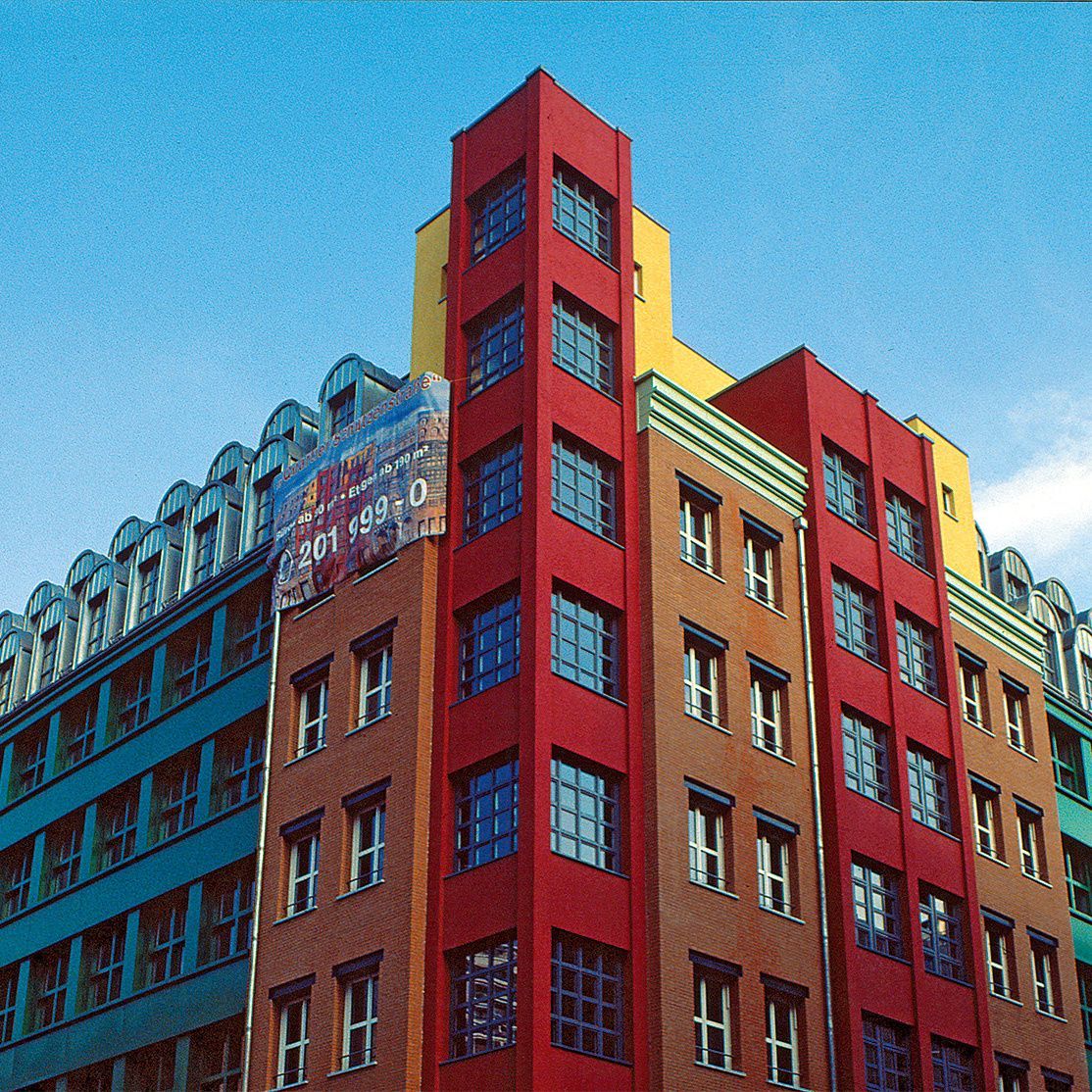 Colorful modern building facade with red, yellow, blue, and brown sections against a blue sky