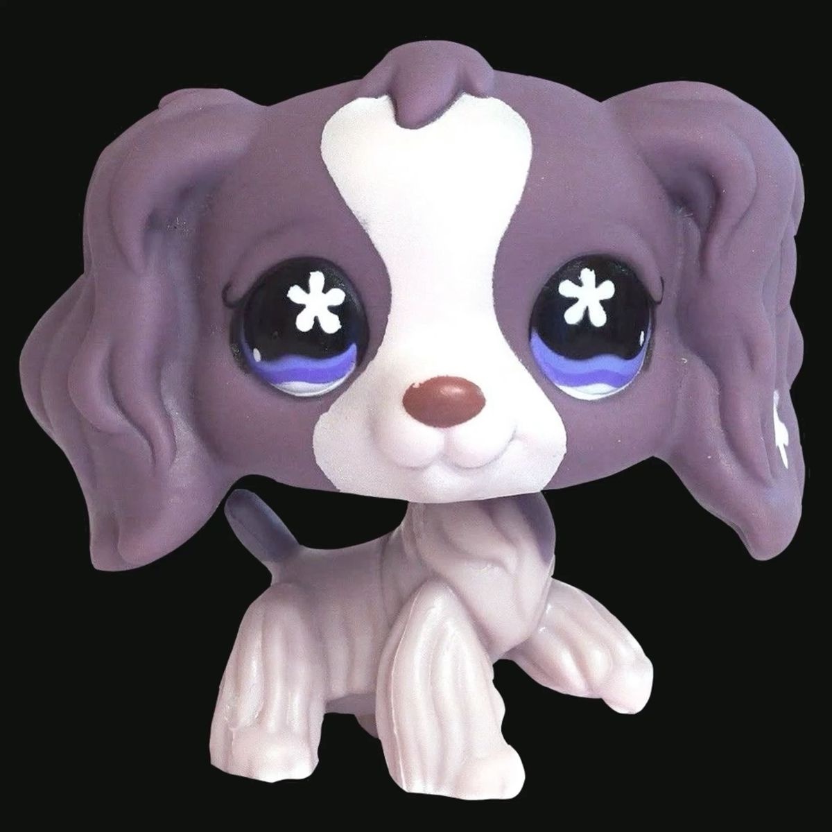 Purple and white toy dog figurine with large blue eyes on a black background