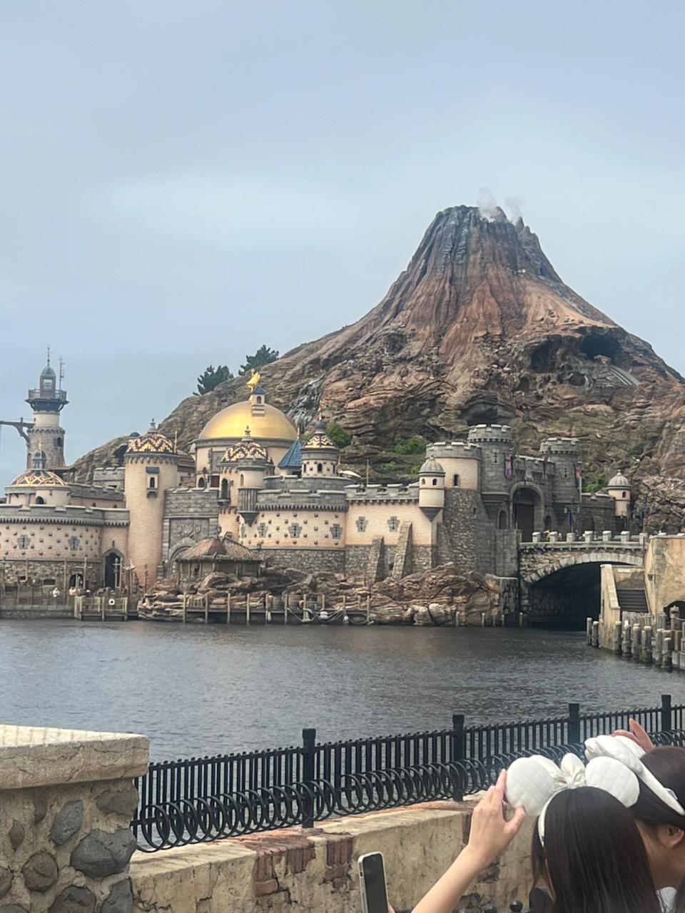 Volcanic mountain behind waterfront buildings and a domed structure by the water
