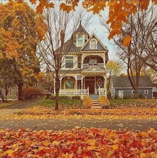 Victorian house with turret surrounded by fall foliage and leaves on ground