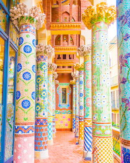 Vibrant mosaic-covered pillars and decorative tiles in Casa Mila's courtyard with ornate patterns and bright colors