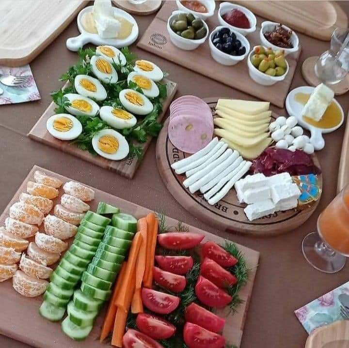Turkish breakfast spread with boiled eggs, sliced cucumbers, tomatoes, cheese platter, and olives on wooden boards