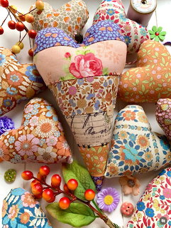 Assorted decorative fabric hearts with floral prints and colorful patterns, displayed with small berries