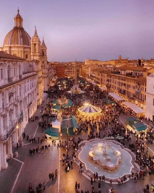 Aerial dusk view of Piazza Navona, Rome, with baroque fountain, carousel lights, and crowds