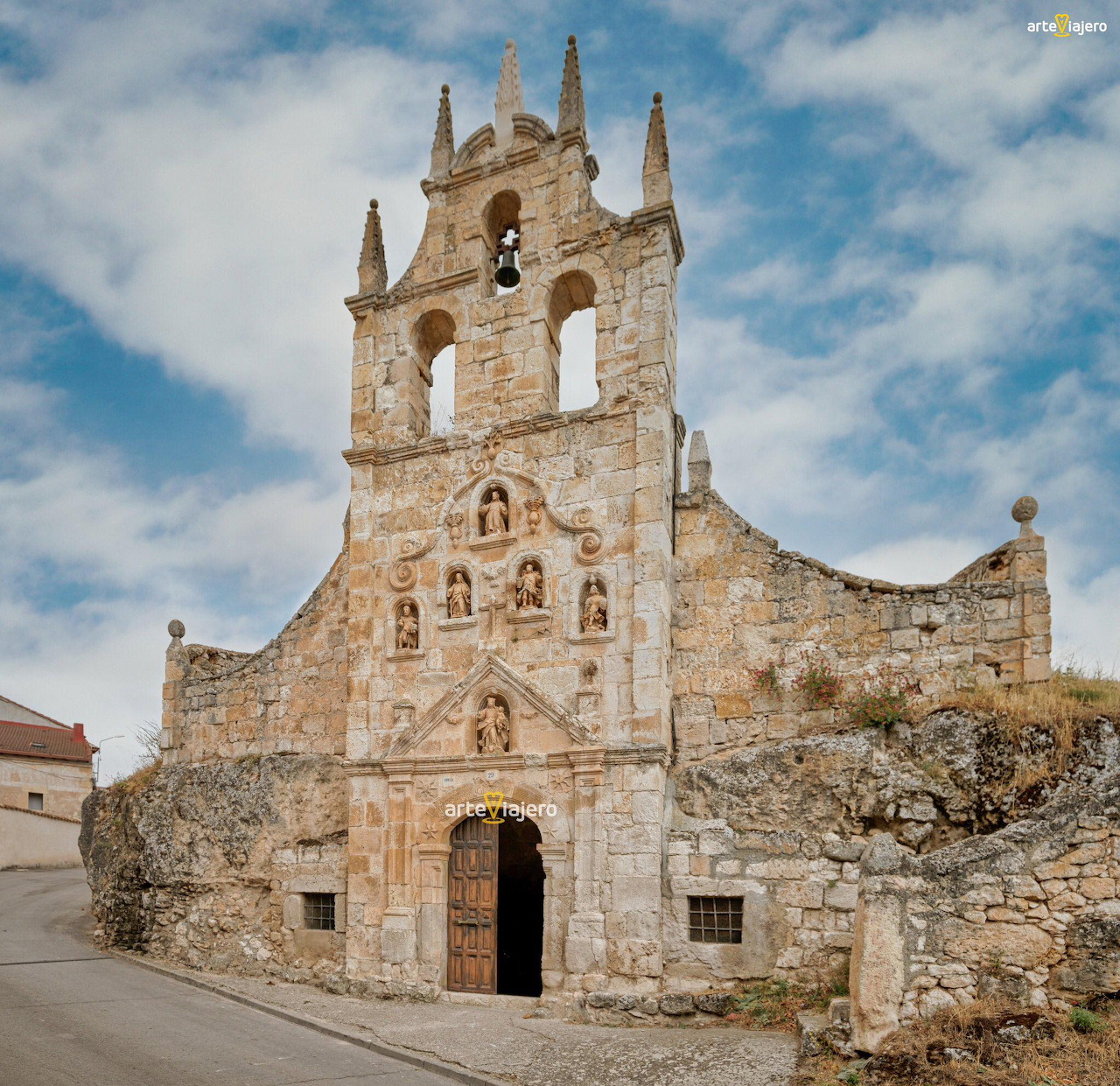 Historic stone church with tall bell tower and ornate facade against blue sky