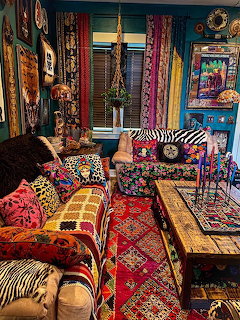Colorful bohemian living room with patterned cushions, ornate rugs, and eclectic wall art in rich jewel tones