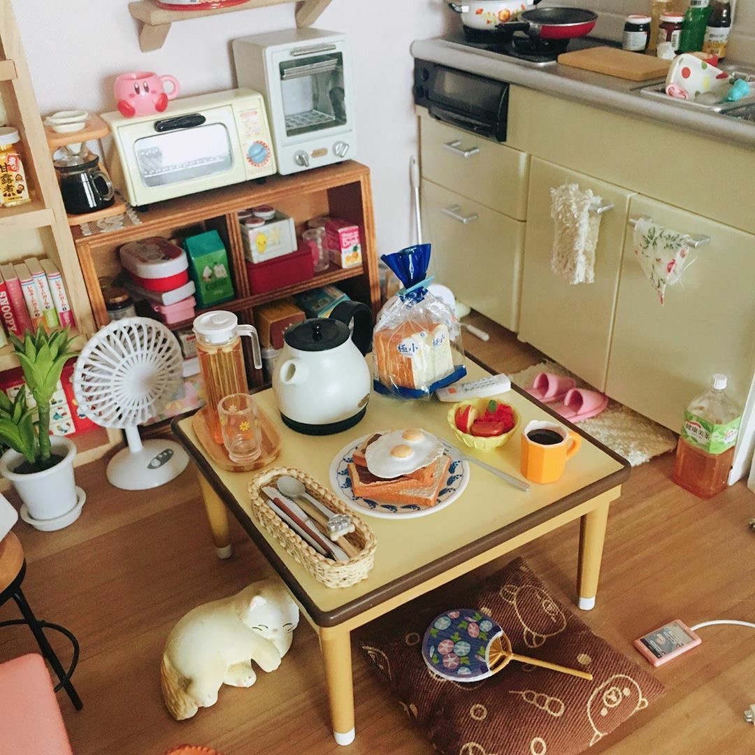 Cozy room with a low breakfast table, kitchen shelf, small appliances, plants, and a white cat on the floor
