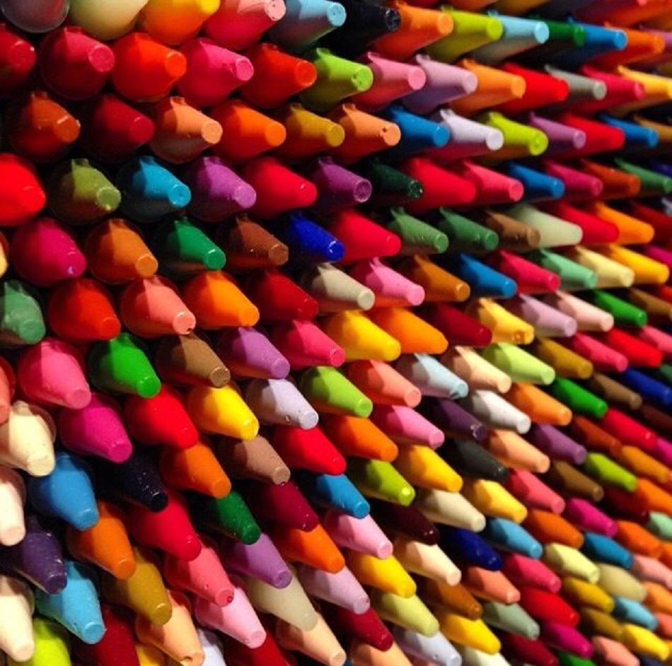 Close-up of many colorful crayons arranged in diagonal rows showing their pointed tips