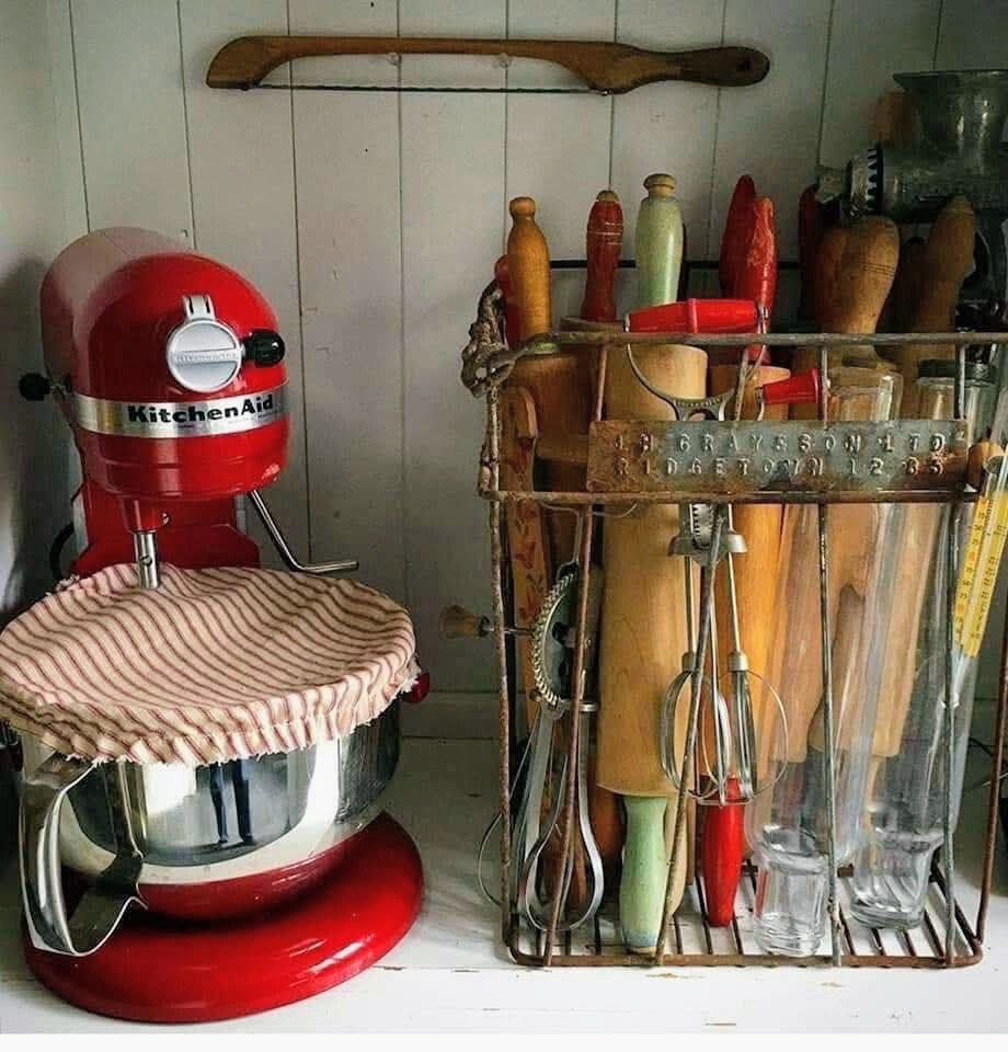 Red stand mixer and vintage kitchen utensils on a rustic shelf
