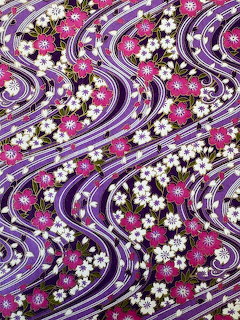 Japanese textile pattern with purple swirling waves and white cherry blossom flowers on dark fabric