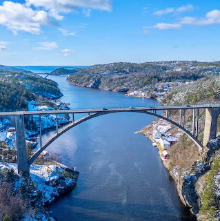 Bridge over a snowy fjord between rocky hills under a blue sky