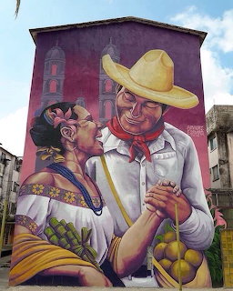 Colorful building mural of a dancing couple in traditional Mexican clothing