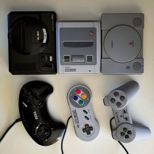 Three retro game consoles with controllers - Sega Genesis, SNES, and PlayStation arranged in a row