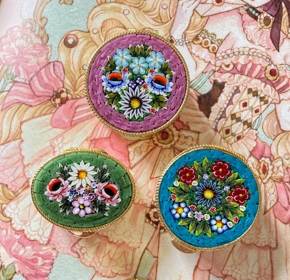 Three decorative floral pill boxes on a pastel vintage illustration background