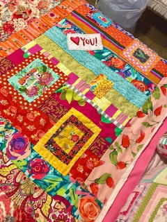 Colorful patchwork quilt with floral patterns and geometric fabric squares in vibrant colors
