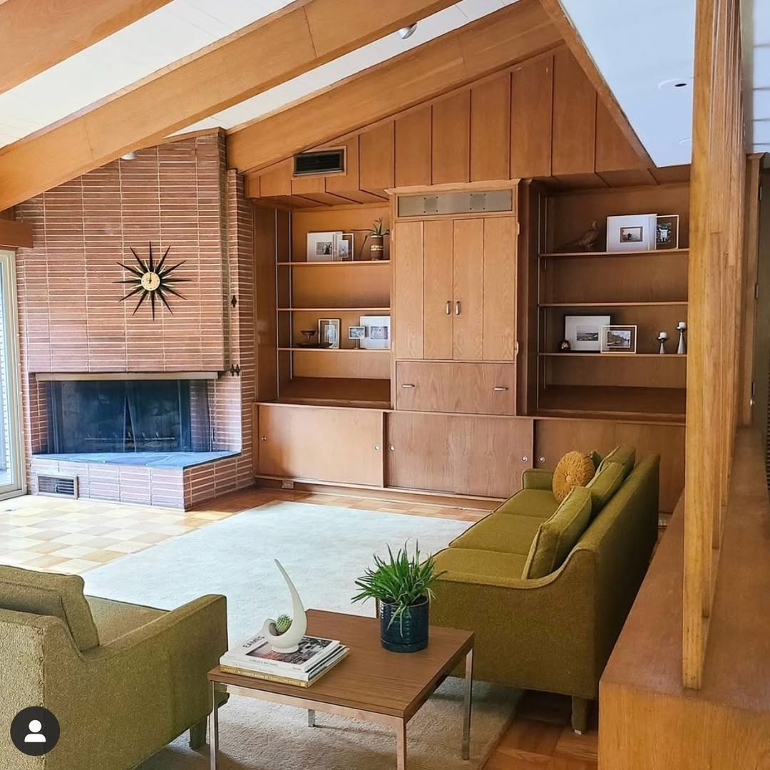 Midcentury modern living room with wood paneling, built-in shelves, fireplace, and green chairs