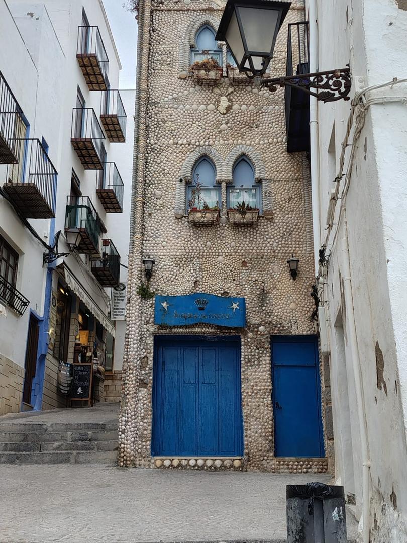 Old stone building with blue doors and shell decorations in narrow Mediterranean street