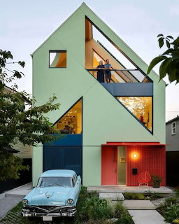 Modern mint green house with sharp angular architecture and triangular windows at dusk